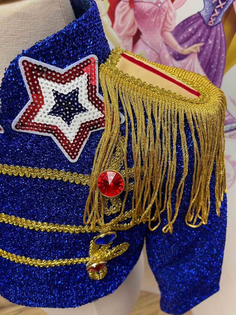 May include: A blue sequined jacket with gold trim and a red star on the front. The jacket has a gold fringe on the shoulder and red and blue jewels.