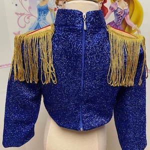 May include: A blue sparkly jacket with gold fringe trim on the shoulders and sleeves. The jacket has a zipper closure at the back.