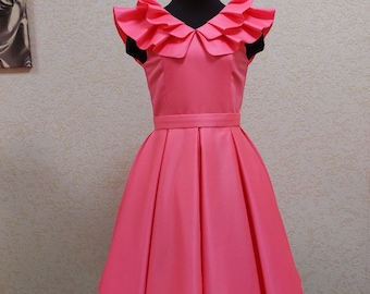 May include: A pink sleeveless dress with a ruffled neckline and a full skirt. The dress is on a mannequin.