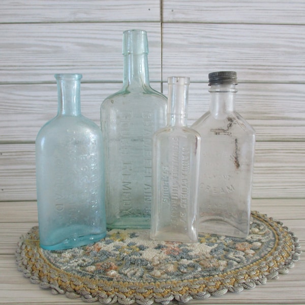 Set of 4 vintage glass bottles, Chamberlain's cough Remedy, Hind's Honey almond cream, Essence of Jamaican ginger, and St. Louis bottle.