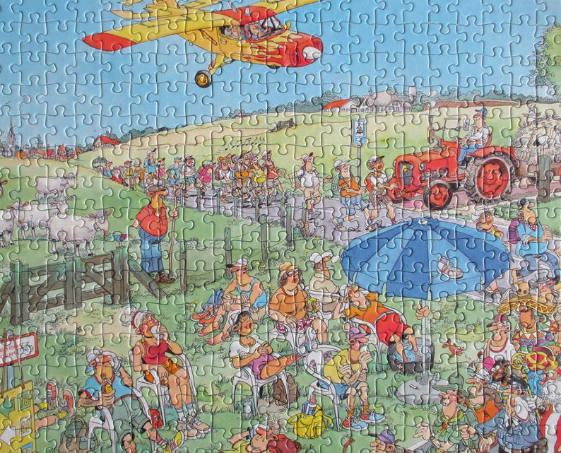 May include: A jigsaw puzzle featuring a cartoon illustration of a rural scene with a yellow airplane flying overhead, a red tractor on a path, a group of people walking, and a crowd of spectators sitting under a large blue umbrella in a field.