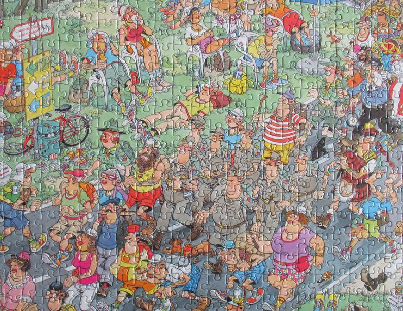 May include: A colorful jigsaw puzzle featuring a crowded outdoor scene with numerous cartoon characters in various outfits, including hikers, cyclists, and people relaxing on grass, with a yellow signpost and a red bicycle visible on the left.