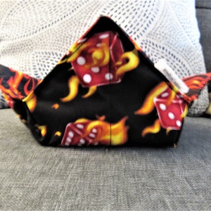 May include: A black fabric bowl with a red dice and flames pattern. The bowl is folded into a triangular shape.