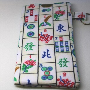 May include: A rectangular fabric pouch with a Mahjong tile pattern in red, green, blue, and black. The pouch has a small loop with a metal clasp and key ring attached. The background is a plain white surface.