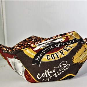 Peut inclure: Un bol en tissu brun avec un motif de grains de café et le texte "Premium Quality Coffee Est. 1927" et "Coffee & Tea Time" imprimé dessus.