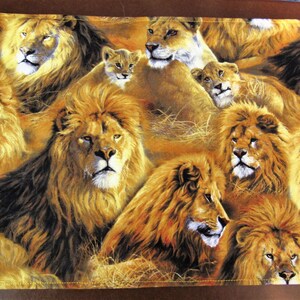 May include: A rectangular placemat featuring a repeating pattern of lions and lionesses in shades of gold, brown, and tan. The design includes several adult lions with full manes and lion cubs. The placemat has a brown border.