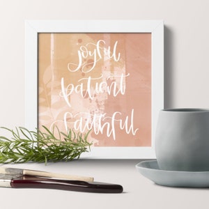 May include: A white framed print with a peach and orange watercolor background. The words "joyful patient faithful" are written in white cursive script.