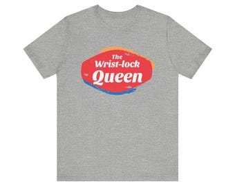 May include: A heather grey t-shirt with a red, blue, and yellow graphic that says "The Wrist-lock Queen."