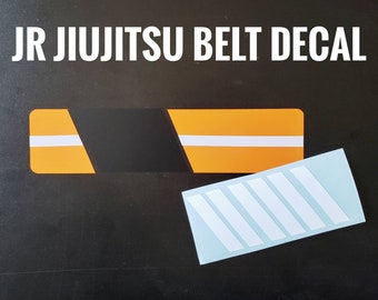 May include: A black and orange Jiu-Jitsu belt decal with the text "JR JIU-JITSU BELT DECAL". The decal is on a black background and is accompanied by a separate sheet of white stripes.