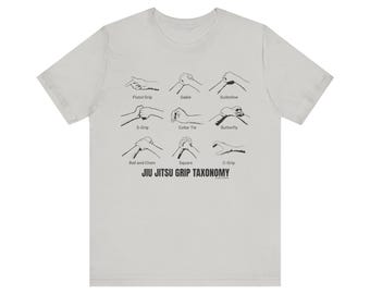 May include: A light gray t-shirt with a black illustration of different jiu-jitsu grip techniques. The text "JIU JITSU GRIP TAXONOMY" is printed below the illustration.