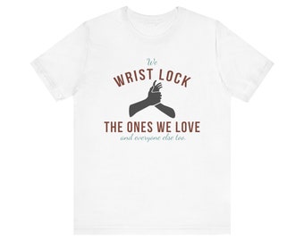 May include: White t-shirt with a graphic of two hands in a wrist lock. The text "We Wrist Lock The Ones We Love and everyone else too." is printed on the shirt.