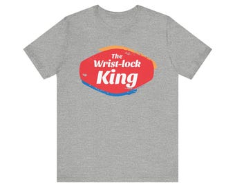 May include: A heather grey t-shirt with a red, orange, and blue graphic that says "The Wrist-lock King" in white text.