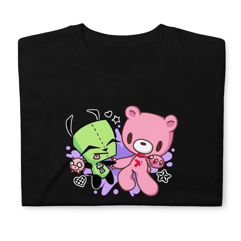 Puede incluir: Camiseta negra con un personaje de dibujos animados verde y un oso de peluche rosa con un coraz&oacute;n rojo y una huella de mano ensangrentada. Los personajes est&aacute;n rodeados de salpicaduras moradas y blancas.