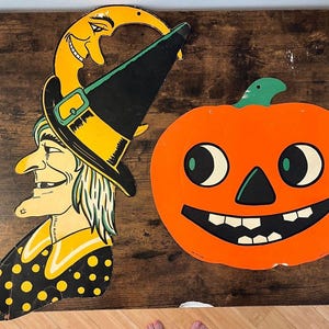 May include: Two vintage-style Halloween wall decorations featuring a witch and a pumpkin. The witch has a yellow crescent moon hat, black pointed hat, and black polka-dot shirt. The orange pumpkin has a green stem and a wide, smiling face.