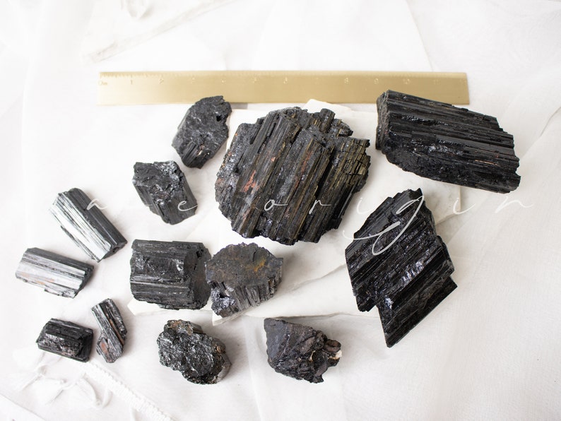 May include: A collection of black tourmaline crystals, also known as schorl, with a variety of shapes and sizes. The crystals are raw and unpolished, with a natural, rough texture.