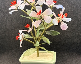 青磁の陶器鉢に入った、ヴィンテージの翡翠と紫色のガラスの花の盆栽。