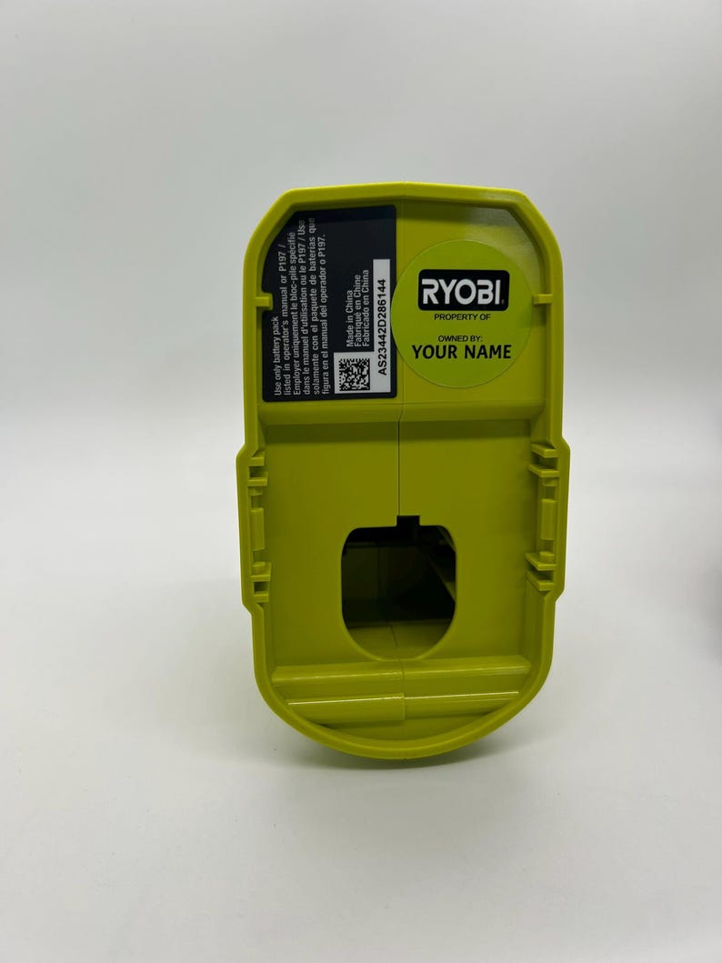Pu&ograve; includere: Un pacco batteria Ryobi verde lime con forma rettangolare. Il pacco ha un adesivo con la scritta "PROPERTY OF YOUR NAME" e "RYOBI". Il pacco ha anche un adesivo con testo in inglese, francese e spagnolo.