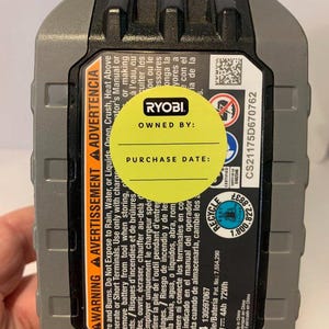 Pu&ograve; includere: Un pacco batteria agli ioni di litio Ryobi 18V nero e grigio con un adesivo giallo che dice "Di propriet&agrave; di:" e "Data di acquisto:". La batteria ha etichette di avvertimento in inglese, francese e spagnolo. La batteria &egrave; 4Ah 72Wh.