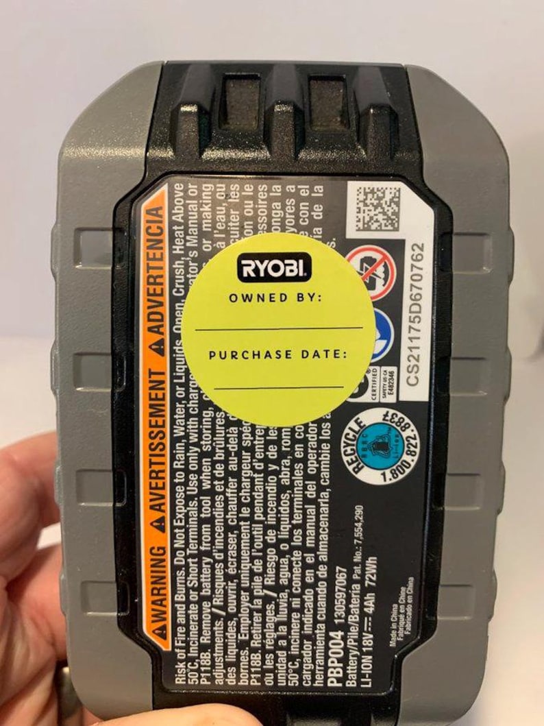 Pu&ograve; includere: Un pacco batteria agli ioni di litio Ryobi 18V nero e grigio con un adesivo giallo che dice "Di propriet&agrave; di:" e "Data di acquisto:". La batteria ha etichette di avvertimento in inglese, francese e spagnolo. La batteria &egrave; 4Ah 72Wh.