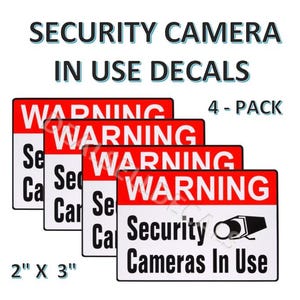 May include: Four red and white warning signs with the text "WARNING Security Cameras In Use" and a black and white illustration of a security camera. The signs are 2 inches by 3 inches.