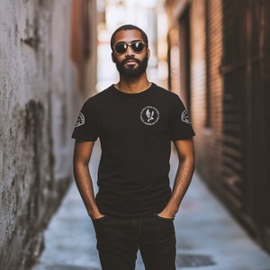 May include: A man wearing a black t-shirt with a white graphic of a bird and the text "Los Angeles Police Department" on the front. He is wearing black jeans and sunglasses.