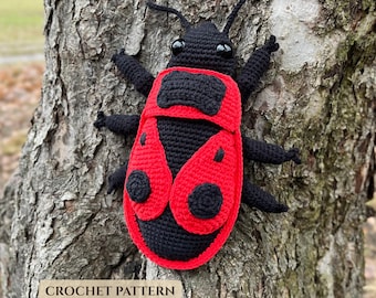 May include: A handmade crochet beetle toy featuring a black body with a bright red wing casing and black circular spots. The insect has two antennae, six legs, and two shiny black eyes. The text CROCHET PATTERN is printed at the bottom left.