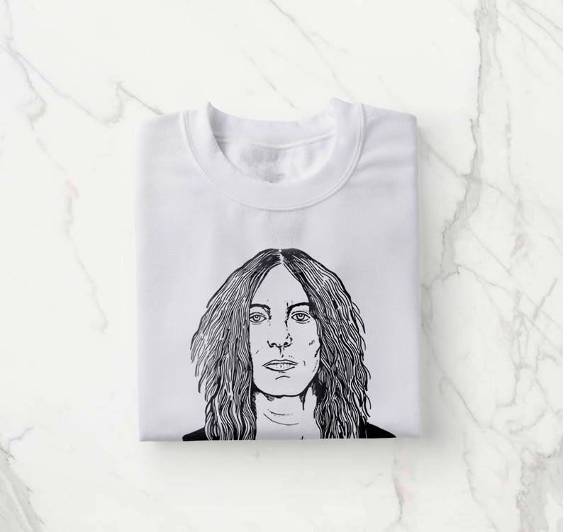 Pu&ograve; includere: Maglietta bianca con un disegno in bianco e nero di una persona con i capelli lunghi.