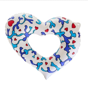 May include: White heart-shaped inflatable pool float with a large heart-shaped cutout in the center. The float is decorated with blue and turquoise abstract shapes and small red hearts. The float is designed for use in a swimming pool or at the beach.