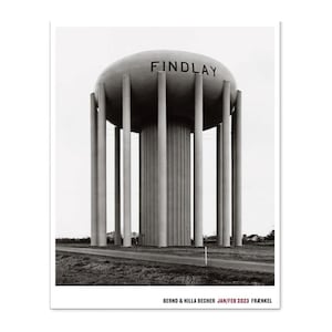 May include: Black and white photograph of a water tower with the word "FINDLAY" on top. The tower is supported by multiple cylindrical columns. The image is set against a cloudy sky and a road.