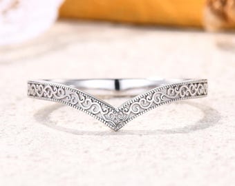 May include: A silver-toned chevron-shaped ring featuring an intricate, repeating scrollwork pattern engraved along the entire outer band. The metal has a polished finish with recessed details that highlight the delicate, continuous swirling design.