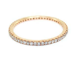 May include: A delicate gold band ring with a row of small, clear diamonds set around the entire band.