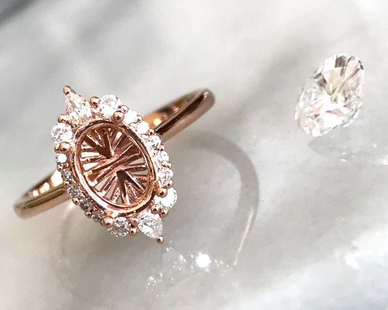 May include: A rose gold ring setting with a pave diamond halo and a pear-shaped center stone setting. The ring is shown next to a loose pear-shaped diamond.