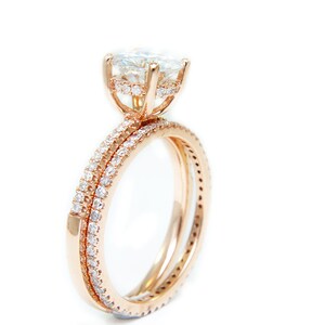 May include: A rose gold engagement ring set with a large, round, clear center stone and smaller stones set in the band.