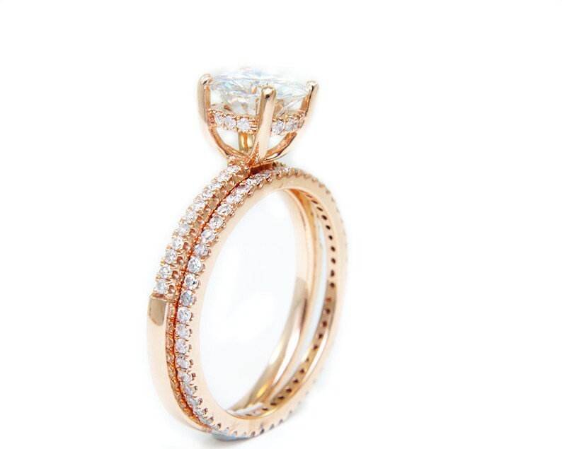 May include: A rose gold engagement ring set with a large, round, clear center stone and smaller stones set in the band.