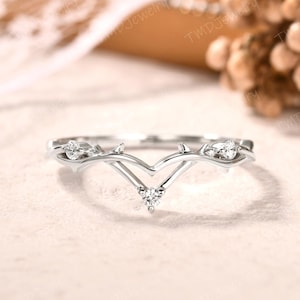 Può includere: Un delicato anello d'argento con un design a forma di V adornato con tre piccoli diamanti. L'anello è progettato per assomigliare a un ramo spinoso con foglie.