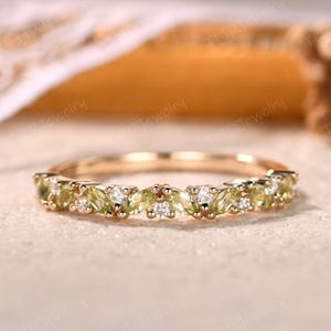 May include: A gold band ring featuring alternating peridot and diamond gemstones. The peridot stones are a light green color, and the diamonds are clear. The ring is set with multiple gemstones, creating a delicate and elegant design.