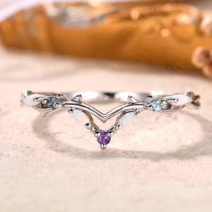 May include: A silver-toned ring with a V-shaped design. The ring features white, blue, and purple gemstones. The ring has a delicate, nature-inspired aesthetic.