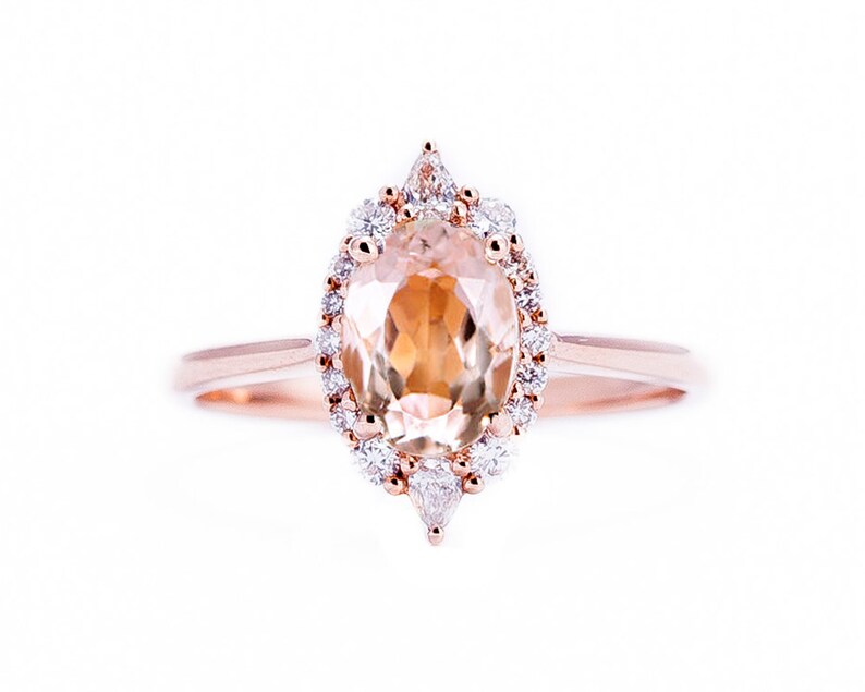 May include: A rose gold ring with a large oval-shaped topaz gemstone surrounded by a halo of smaller diamonds.