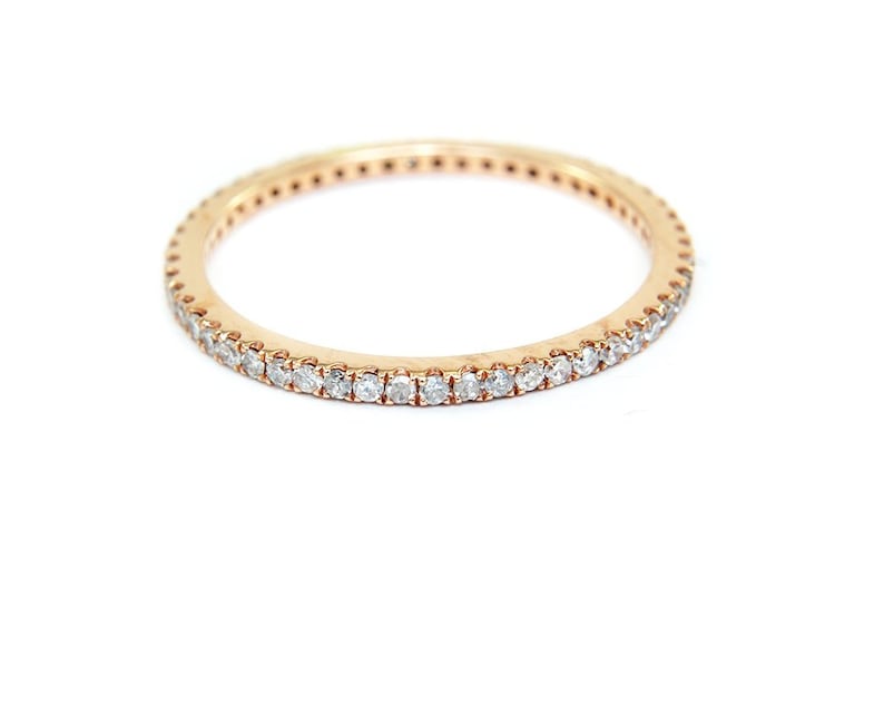 May include: A delicate gold band ring with a row of small, clear diamonds set around the entire band.