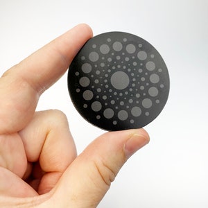 May include: A black round disc with a concentric circle pattern of gray dots.