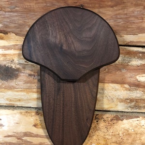 May include: A dark brown wooden wall mount for taxidermy. The mount is shaped like a deer head and has a smooth, polished finish.