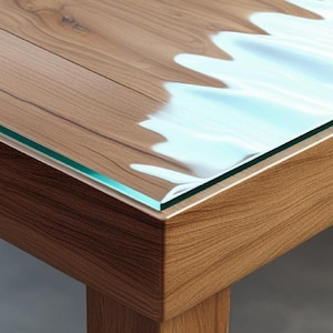 Op de afbeelding: Houten tafel met glazen blad. De tafel heeft een lichtbruine houtnerf afwerking op de zijkanten en poten. Het glazen blad heeft een golvend, lichtblauw ontwerp aan één kant, wat een uniek visueel effect creëert.