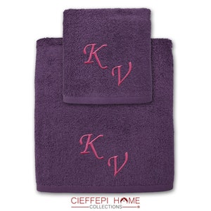Può includere: Due asciugamani viola con le iniziali "KV" ricamate in rosa su ciascuno. Gli asciugamani sono piegati uno sopra l'altro. Il marchio "CIEFEEPI HOME COLLECTIONS" è stampato sul fondo degli asciugamani.