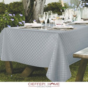 Pode incluir: Uma toalha de mesa quadriculada cinza com um padr&atilde;o em relevo sutil, colocada em uma mesa de madeira com copos e pratos. A toalha de mesa &eacute; feita pela Ciefefpi Home Collections.