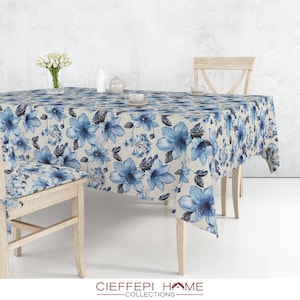 Peut inclure: Une nappe blanche avec un motif floral bleu. La nappe est sur une table en bois avec deux chaises en bois. La nappe est faite d'un tissu doux et durable et est parfaite pour un usage quotidien.