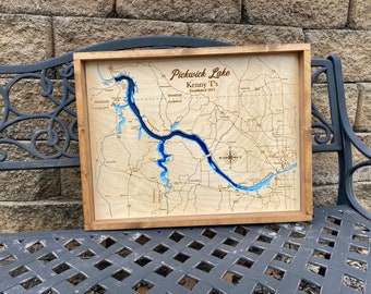 May include: A wooden map of Pickwick Lake with a blue epoxy resin inlay. The map is framed in a rustic brown wood frame. The text "Pickwick Lake Kenny T's Established 2013" is engraved on the map.
