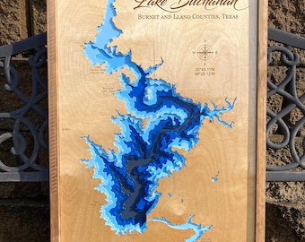 May include: A wooden framed map of Lake Buchanan in Texas, with layered blue and light blue water depth contours. The text "Lake Buchanan" and county names are visible. A compass rose is in the lower right corner.