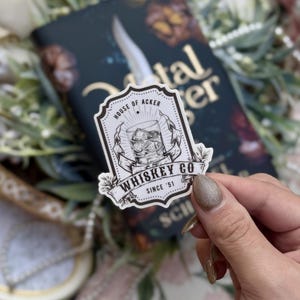 Peut inclure: Un autocollant noir et blanc avec le texte "Whiskey Co Since '51" et une illustration d'un verre de whisky avec des glaçons. L'autocollant comprend également le texte "House of Acker".