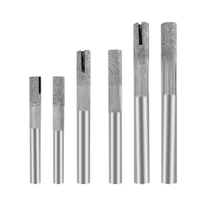 May include: A set of six cylindrical drill bits arranged by size, each featuring a smooth silver metal shank and a textured, abrasive diamond-coated tip with a vertical slot cut into the top edge for drilling through hard materials.