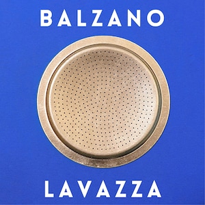 May include: A circular, perforated metal coffee filter with the word "BALZANO" at the top and "LAVAZZA" at the bottom, set against a blue background. The filter has a series of small holes throughout its surface.